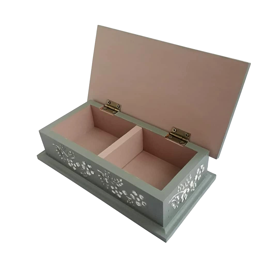 Caja rectangular de color verde grisáceo por fuera y rosado por dentro; con dos espacios para guardar sobres de té o para usar como alhajero. Tiene detalles en tres dimensiones con motivo floral. Las dimensiones de la cajita son: 21 centímetros por 11 centímetros por 5,5 centímetros. El material de la caja es MDF y está pintada a mano. El código para comprar la caja es CT06.